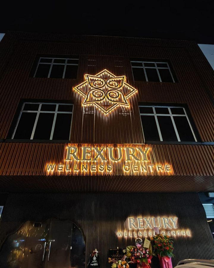 The illuminated Rexury Wellness Centre storefront and signage on Jalan Jaya Putra at night
