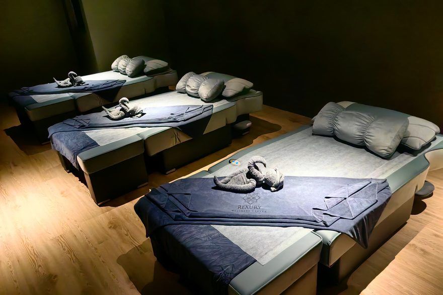 Three made-up massage beds with fresh folded towels in a Rexury treatment room