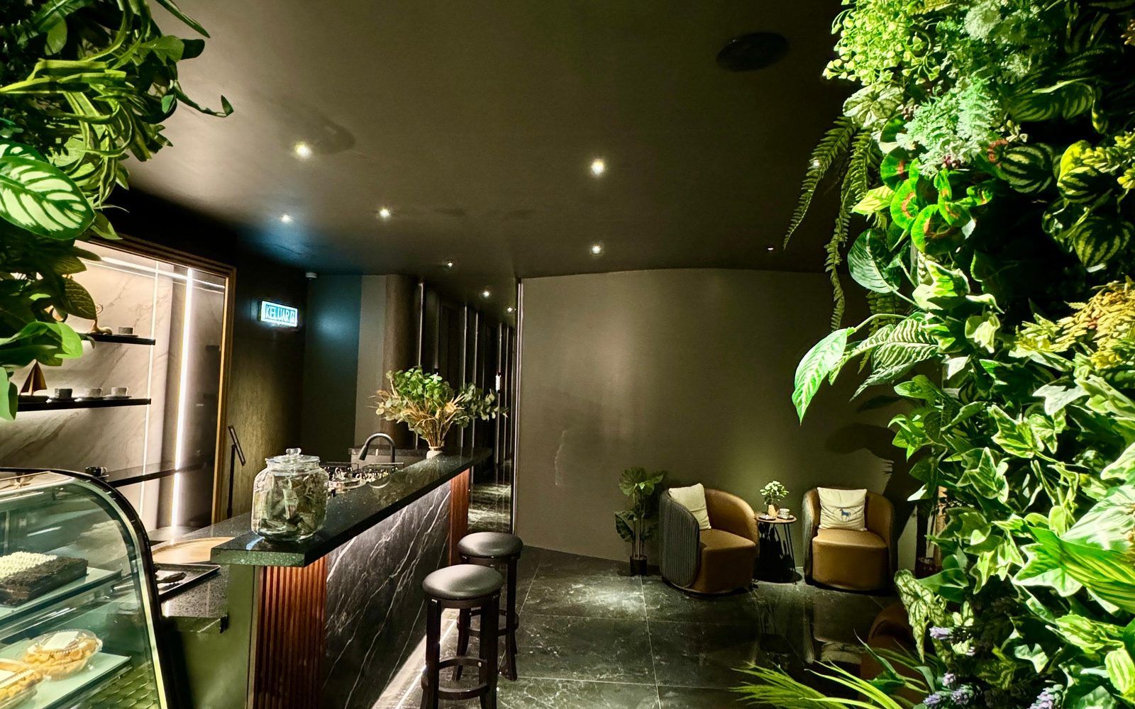 The Rexury lounge with a full-height living plant wall, black marble bar and warm gold uplighting