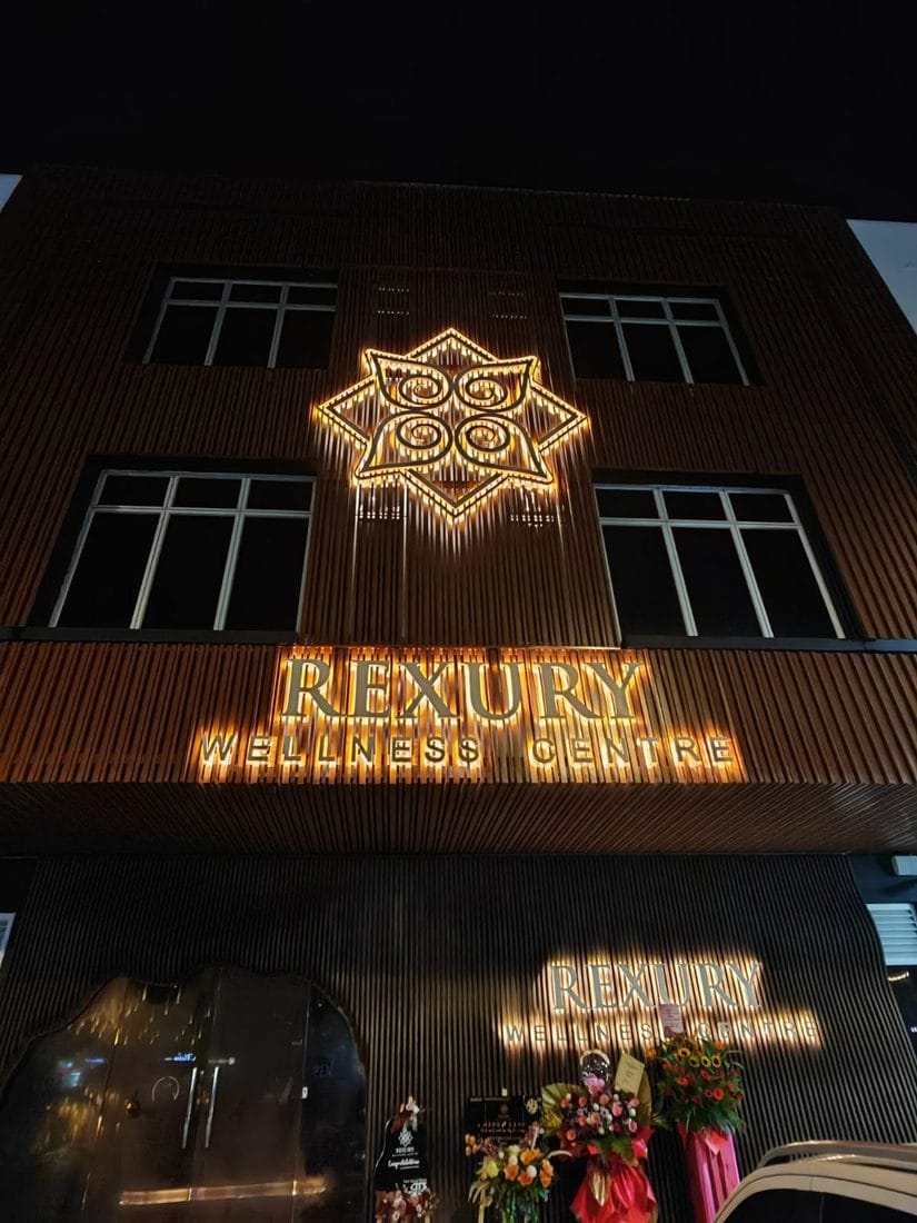 The illuminated Rexury Wellness Centre storefront in Crest Austin, glowing gold against the night