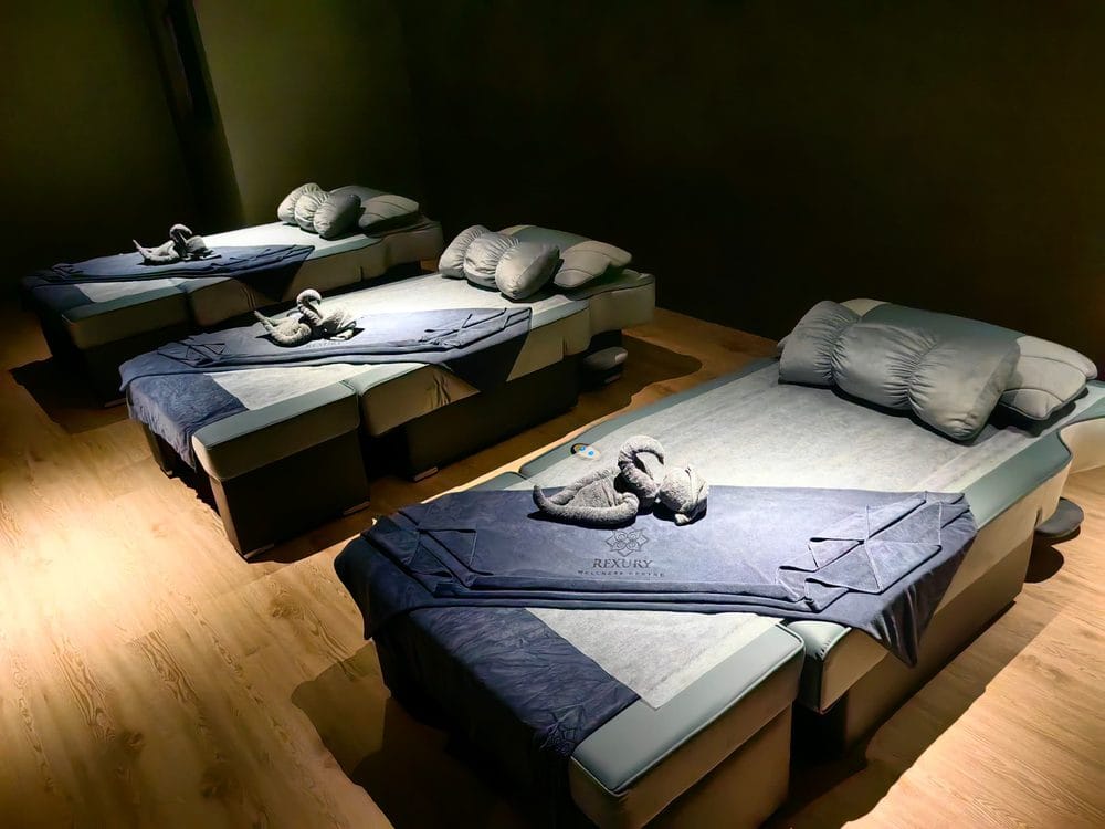 A private treatment room at Rexury, made up with dressed massage beds and Rexury-branded towels under warm low light