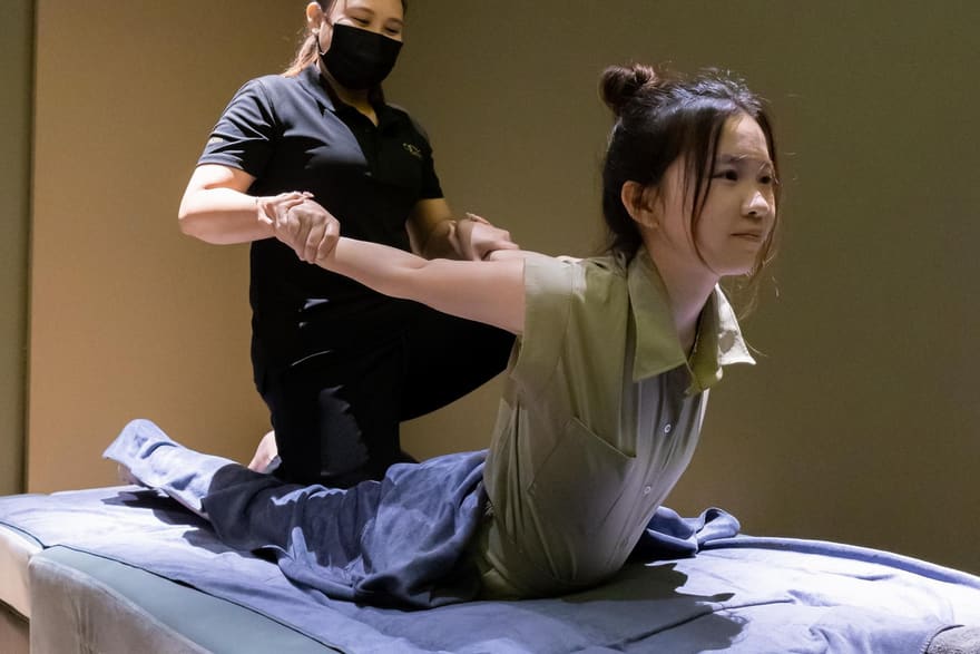 A Rexury therapist performing an assisted full-body stretch on a guest in a private treatment room