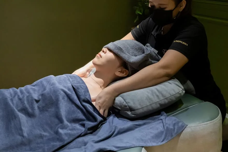 A guest reclining under a warm compress during a shoulders, knees and toes session at Rexury